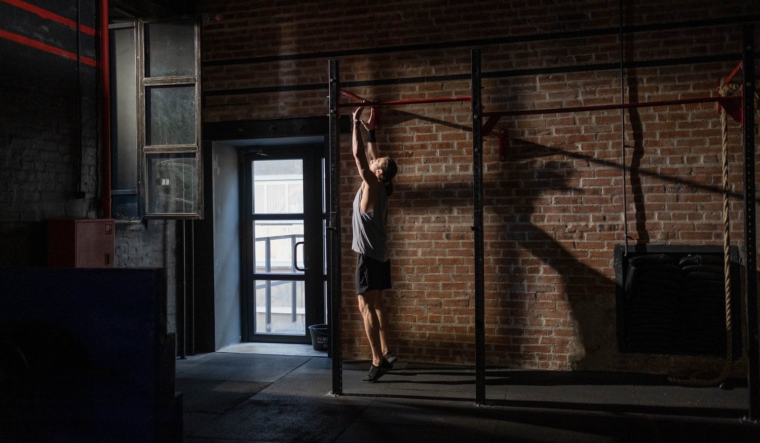 Man doing a pull-up in a dark gym